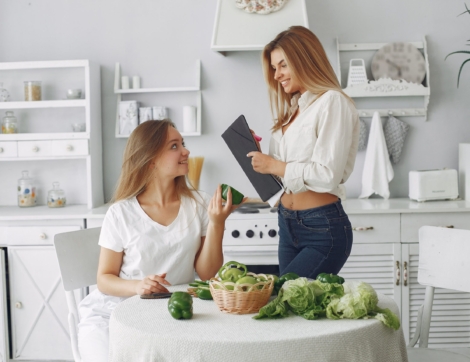 Beautiful and sporty girls in a kitchen with a vegetables